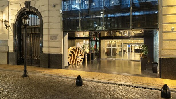 A hotel entrance with a large, decorative archway, a modern glass facade, and a cobblestone ground. - NH Collection Buenos Aires Centro Histórico (Buenos Aires)