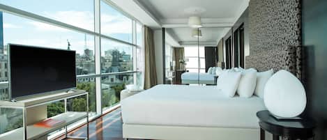 Una habitación de hotel moderna con una cama grande, televisión y vistas a la ciudad.