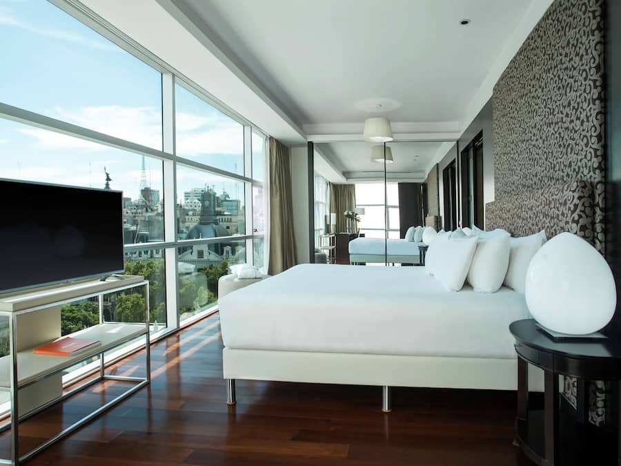 Una habitación de hotel moderna con una cama grande, televisión y vistas a la ciudad.