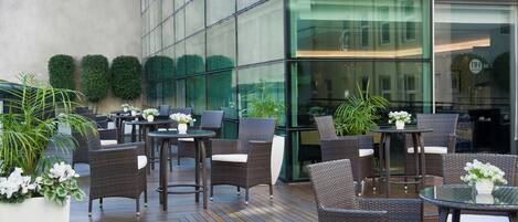 An outdoor seating area with wicker furniture and potted plants.