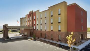 A multi-story hotel with a brick facade, a welcoming entrance, and a parking lot.