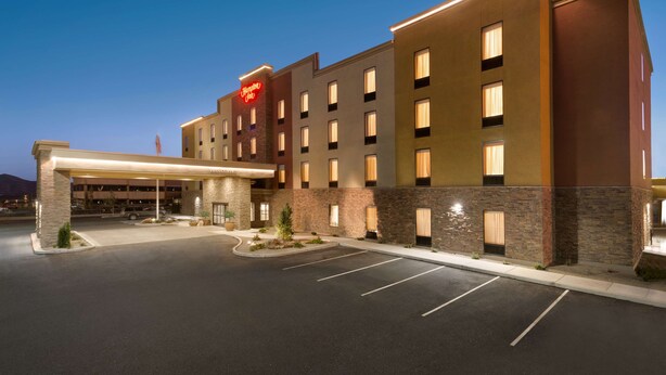 Een hotel met een modern design, met een opvallende ingang, een overdekte doorgang, meerdere verdiepingen en een goed verlichte gevel.