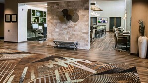 A hotel lobby with a stone wall, a bench, a reception desk, and a bar area. - Hampton Inn & Suites Hudson (Hudson)