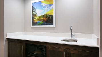 A kitchen with a white countertop, stainless steel sink, and a built-in microwave.
