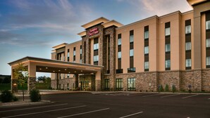 A Hampton Inn Suites hotel with a modern design, featuring a stone facade and a covered entrance. - Hampton Inn & Suites Hudson (Hudson)