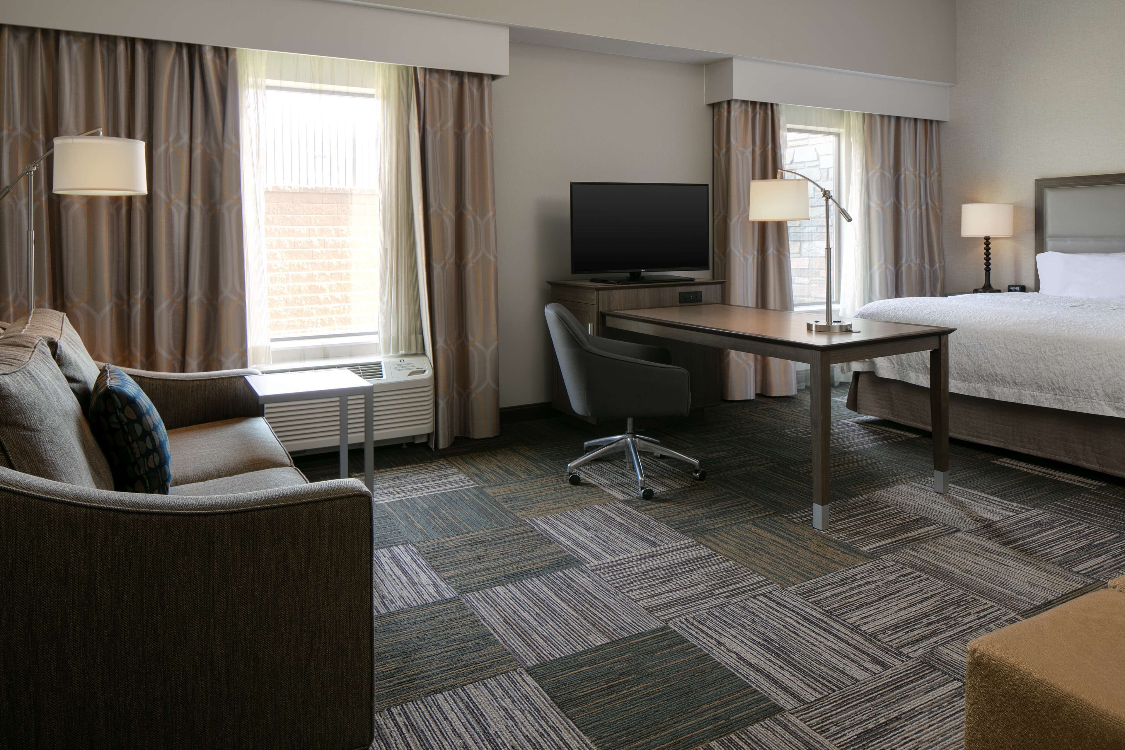 Een hotelkamer met een bed, een bureau met een televisie, een stoel en een bank.
