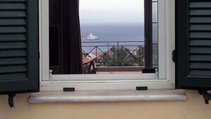 A window with black shutters, a view of the sea, and a balcony railing. - Letos Villas (Paxos)