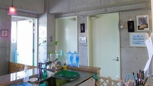 A kitchen with a sink, countertop, and hanging light fixture. - Guest House Sea glass (Itoman)