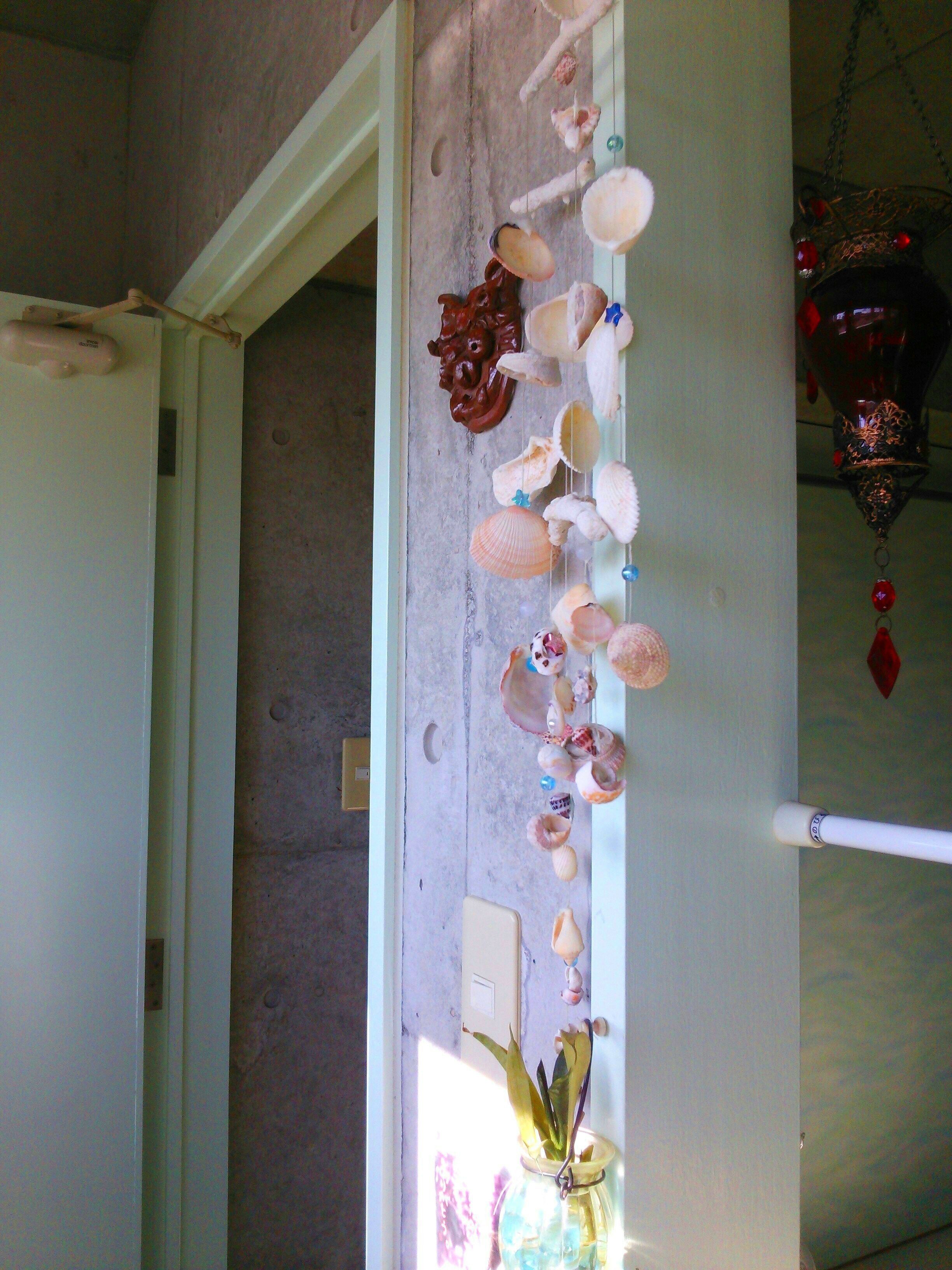 Un couloir orné d’un mur décoratif où sont disposés des coquillages et d’un objet suspendu.