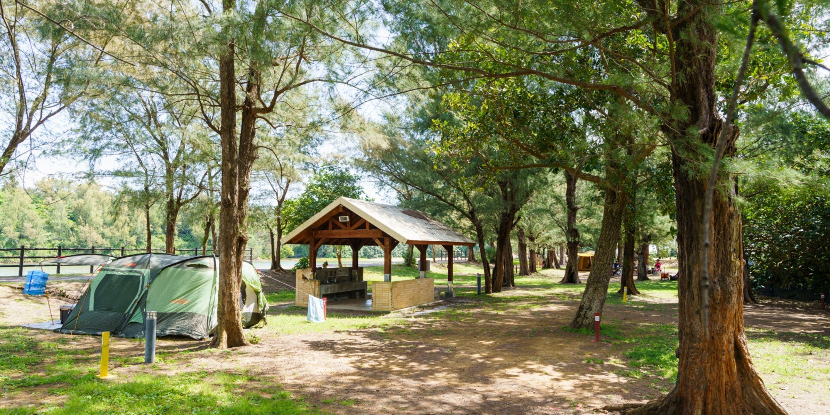 A campsite with tents, a wooden pavilion, and a picnic table.