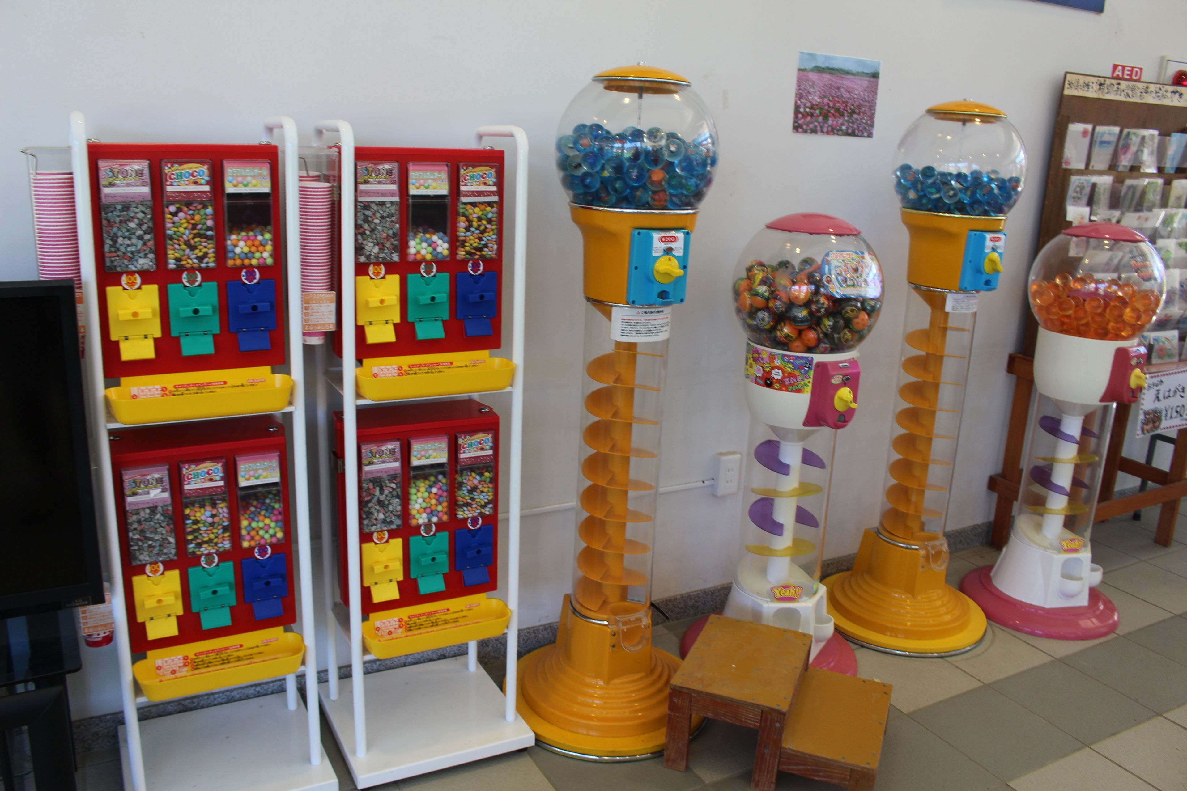 Una hilera de máquinas expendedoras de bolitas de chicle y una máquina de venta automática con diversas botanas y dulces.