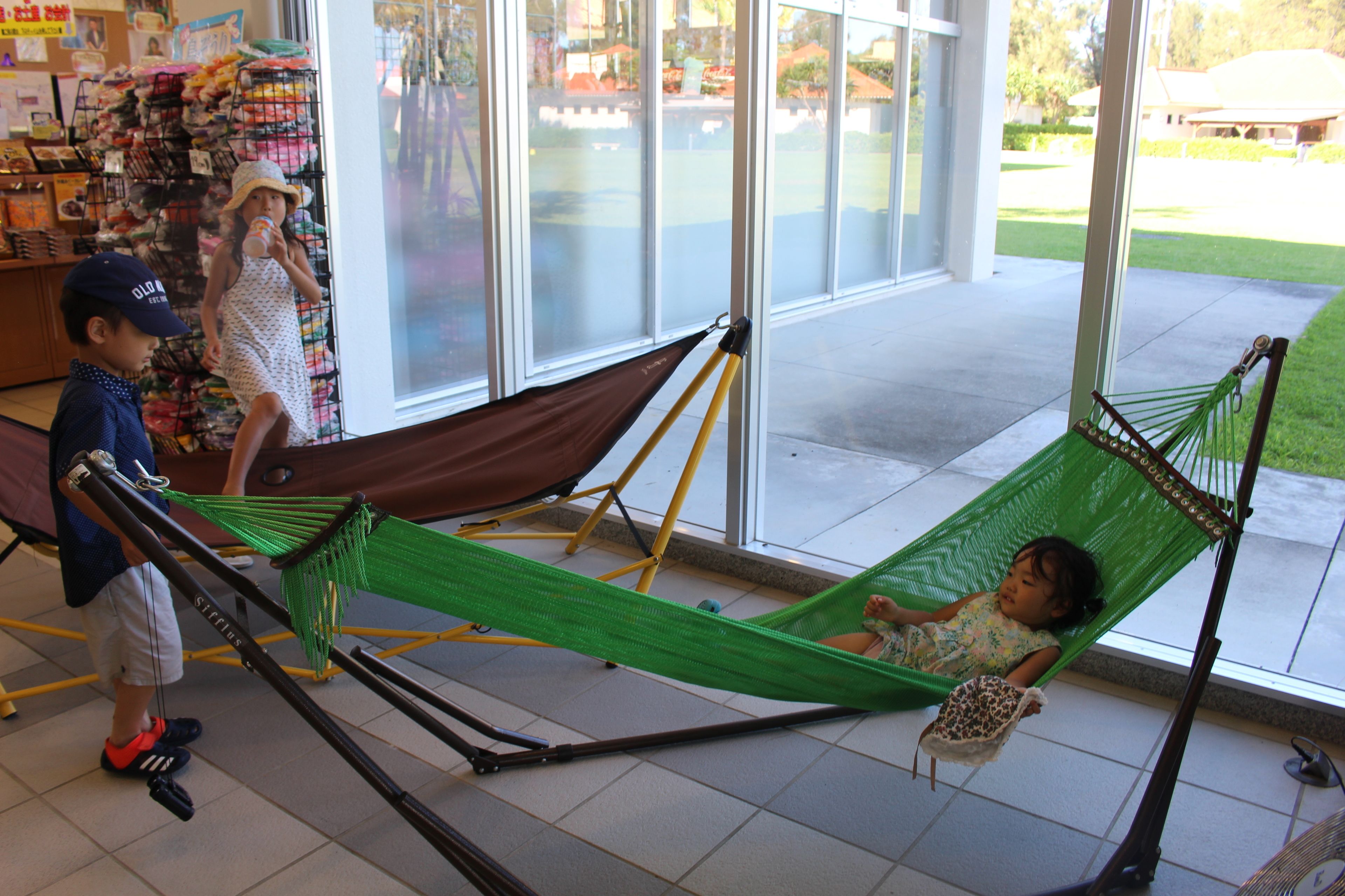 A hammock set up in a room with a tiled floor and large windows.