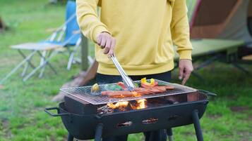Iemand barbecuet worstjes op een buitenbarbecue.