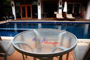 A glass-top table with a pool in the background. - Baan Soontree Resort (Chiang Rai)