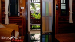 Una habitación de madera con una cama, un banco y vistas a un jardín a través de una puerta.