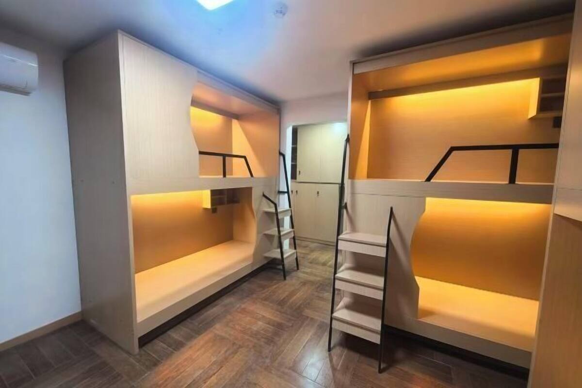 A room with bunk beds, a staircase, and a wooden floor.