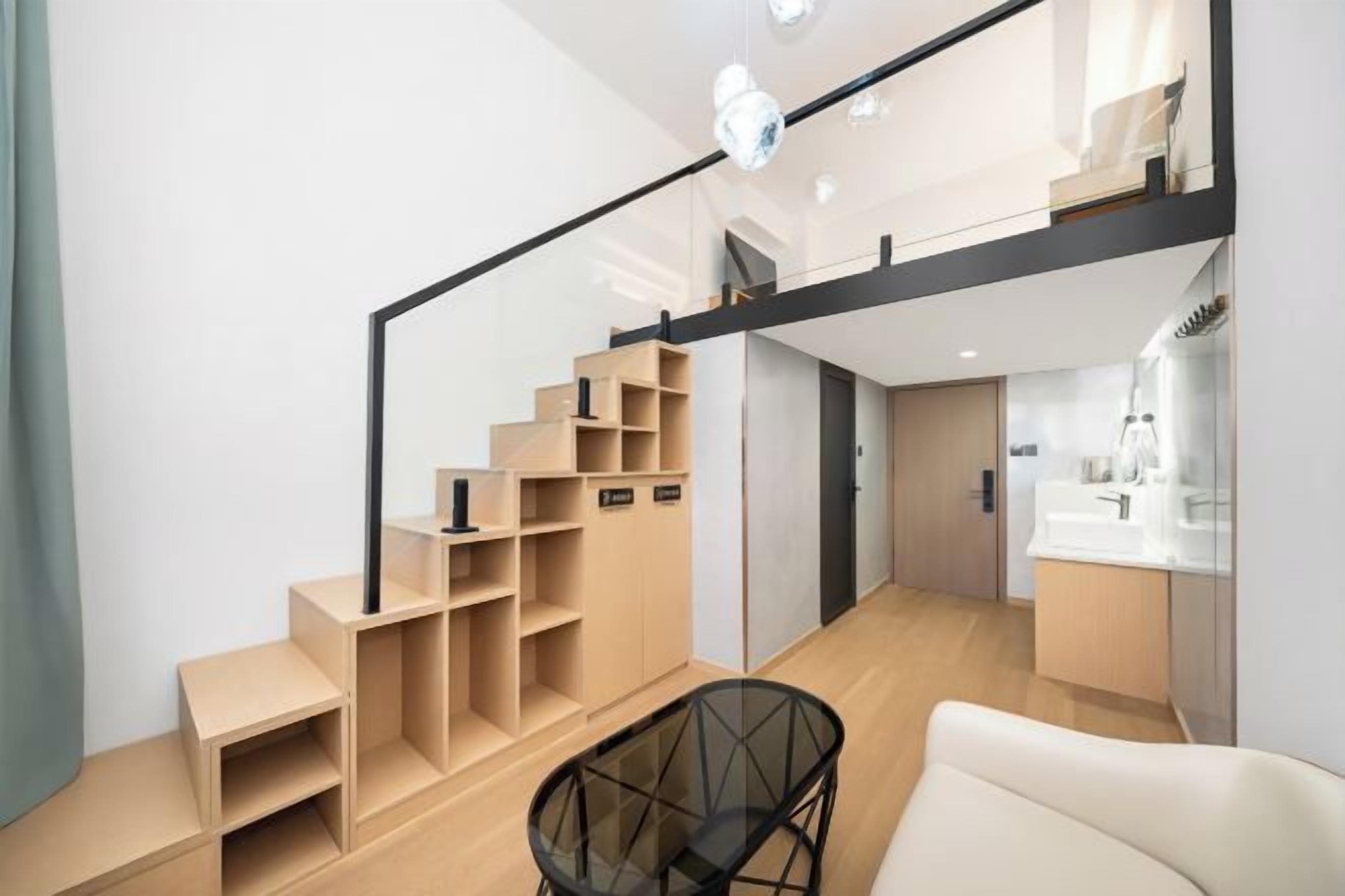 Un interior moderno con una escalera, una mesa de vidrio y un sofá blanco.