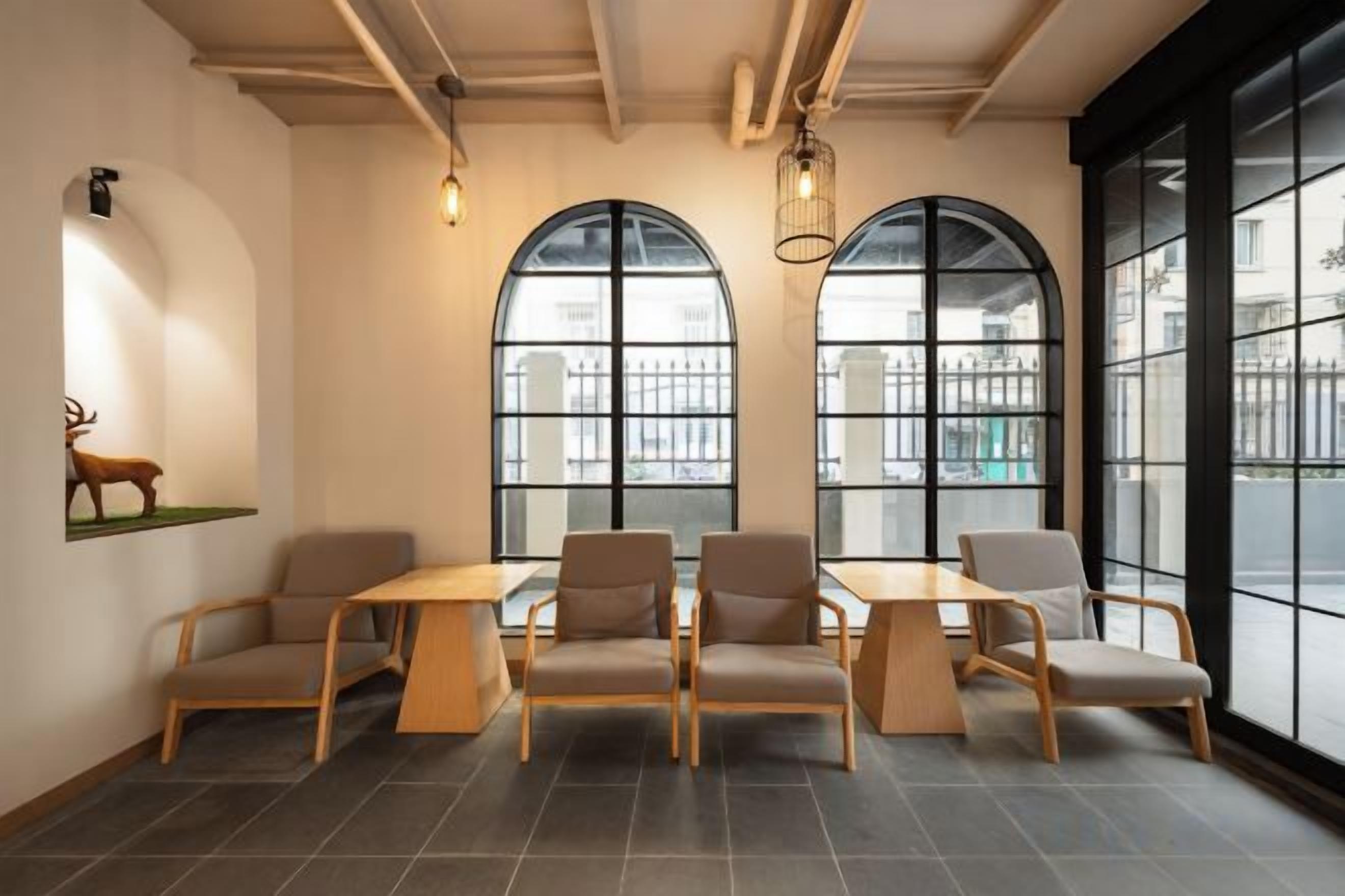 A room with a long table and six chairs, large arched windows, and a wall-mounted deer sculpture.
