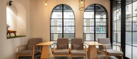 A room with a long table and six chairs, large arched windows, and a wall-mounted deer sculpture.