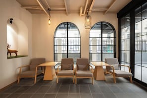 A room with a long table and six chairs, large arched windows, and a wall-mounted deer sculpture.