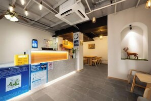 A reception area with a counter, a clock, and a wall-mounted deer sculpture. - Beehome Hostel (Shanghai)