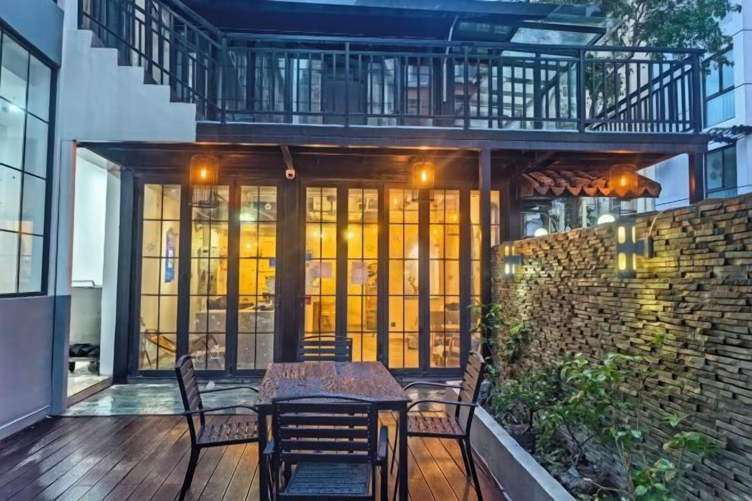 Un patio moderno al aire libre con una mesa y sillas de comedor, un muro de piedra y una puerta de vidrio que da a un espacio interior.