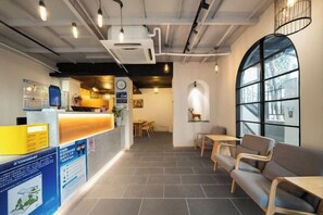 A reception area with a counter, seating, and a large window. - Beehome Hostel (Shanghai)