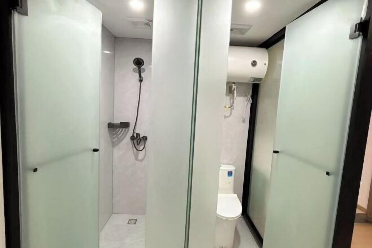 A modern bathroom with a glass partition, a shower, and a toilet.