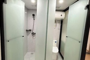A modern bathroom with a glass partition, a shower, and a toilet. - Beehome Hostel (Shanghai)