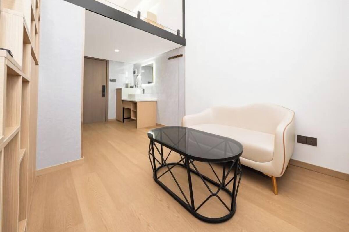 A modern interior with a glass-top table, a sofa, and a wooden floor.