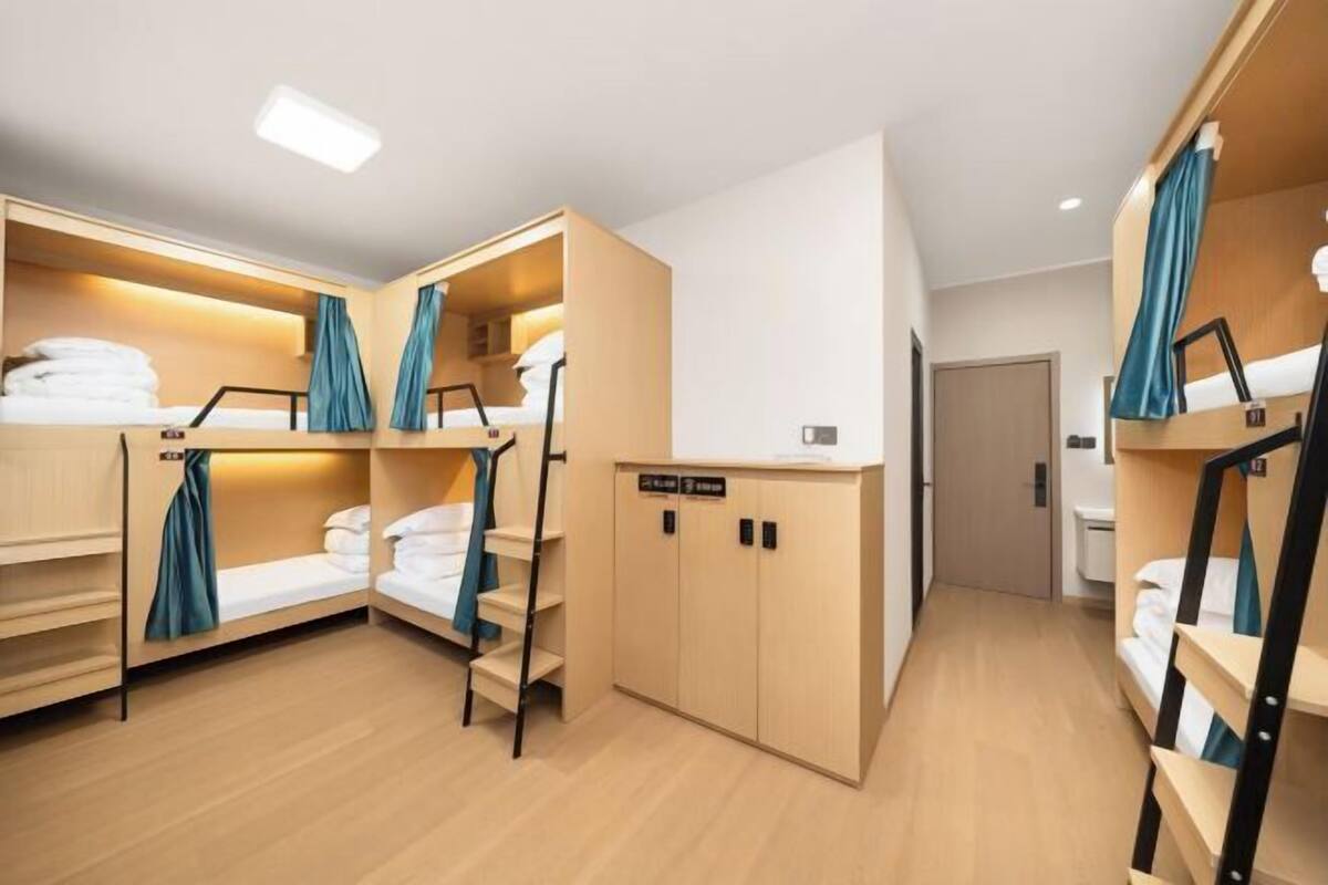 A hotel room with bunk beds, a wardrobe, and a door leading to another room.