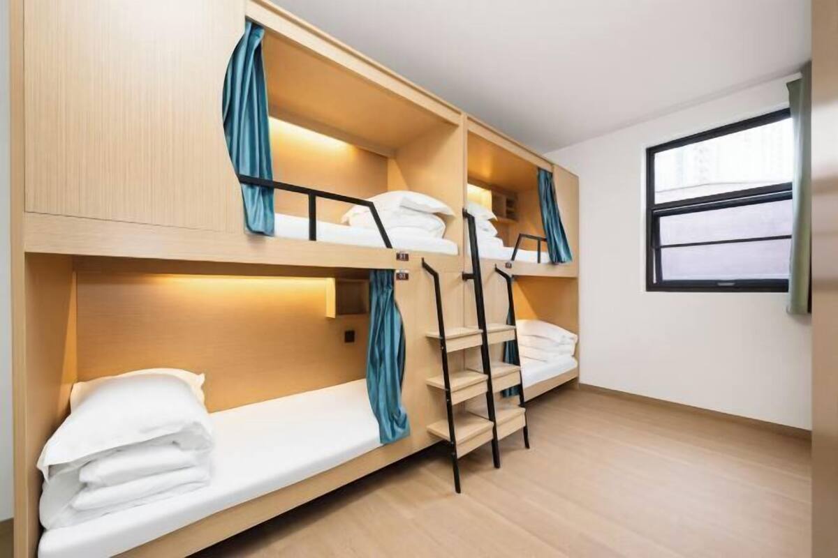 A bunk bed room with wooden walls, a window, and a curtain.