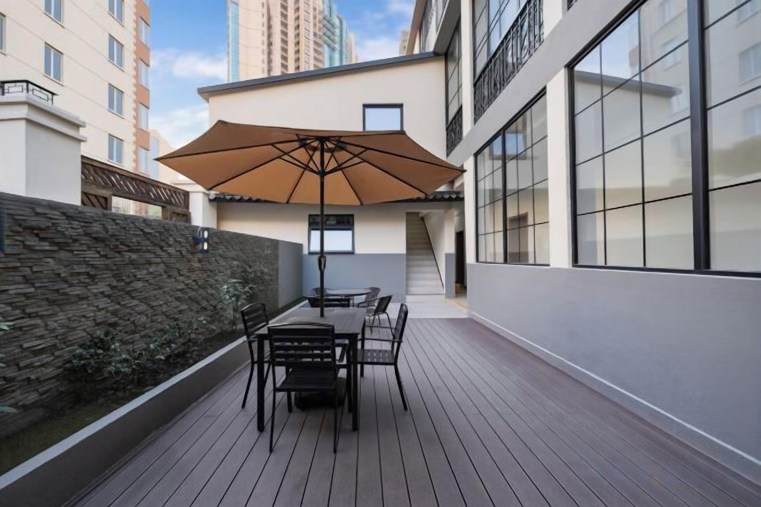 An outdoor patio with a table and chairs, a large umbrella, and a stone wall.