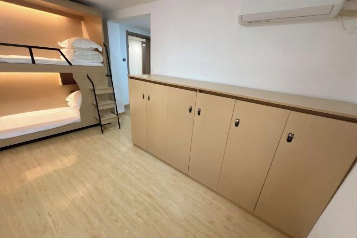 A bunk bed with neatly folded towels, a wooden wardrobe with multiple doors, and a staircase leading to an upper level.