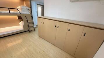 Una cama litera con toallas dobladas cuidadosamente, un armario de madera con varias puertas y una escalera que lleva a un nivel superior.