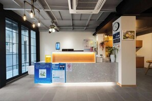 A reception area with a desk, informational posters, a clock, and a large window. - Beehome Hostel (Shanghai)