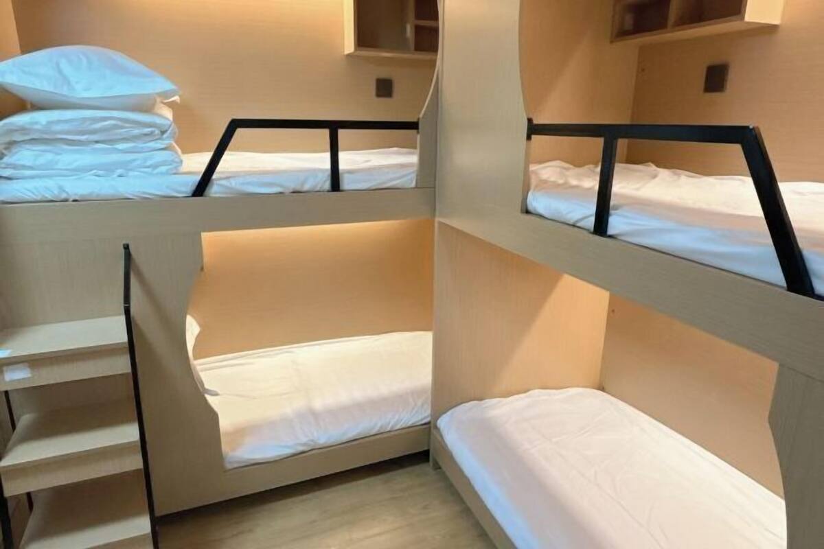 A bunk bed room with a wooden headboard, a small shelf, and a window.