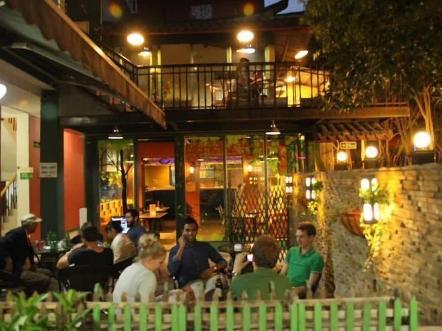 Un área de comedor al aire libre con mesas y sillas, rodeada por una valla de madera y un muro de piedra.
