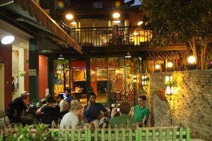 An outdoor dining area with tables and chairs, surrounded by a wooden fence and a stone wall. - Beehome Hostel (Shanghai)