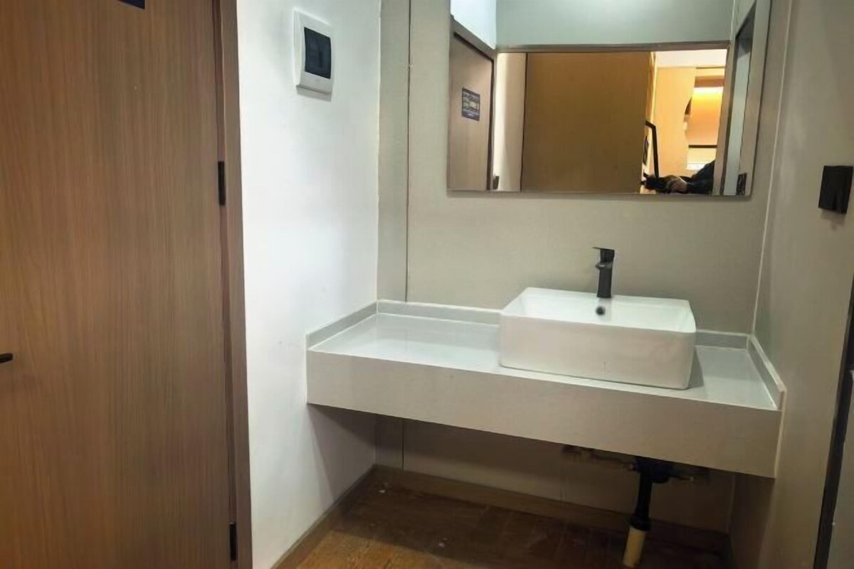 A bathroom with a white sink, a mirror, and a wooden door.