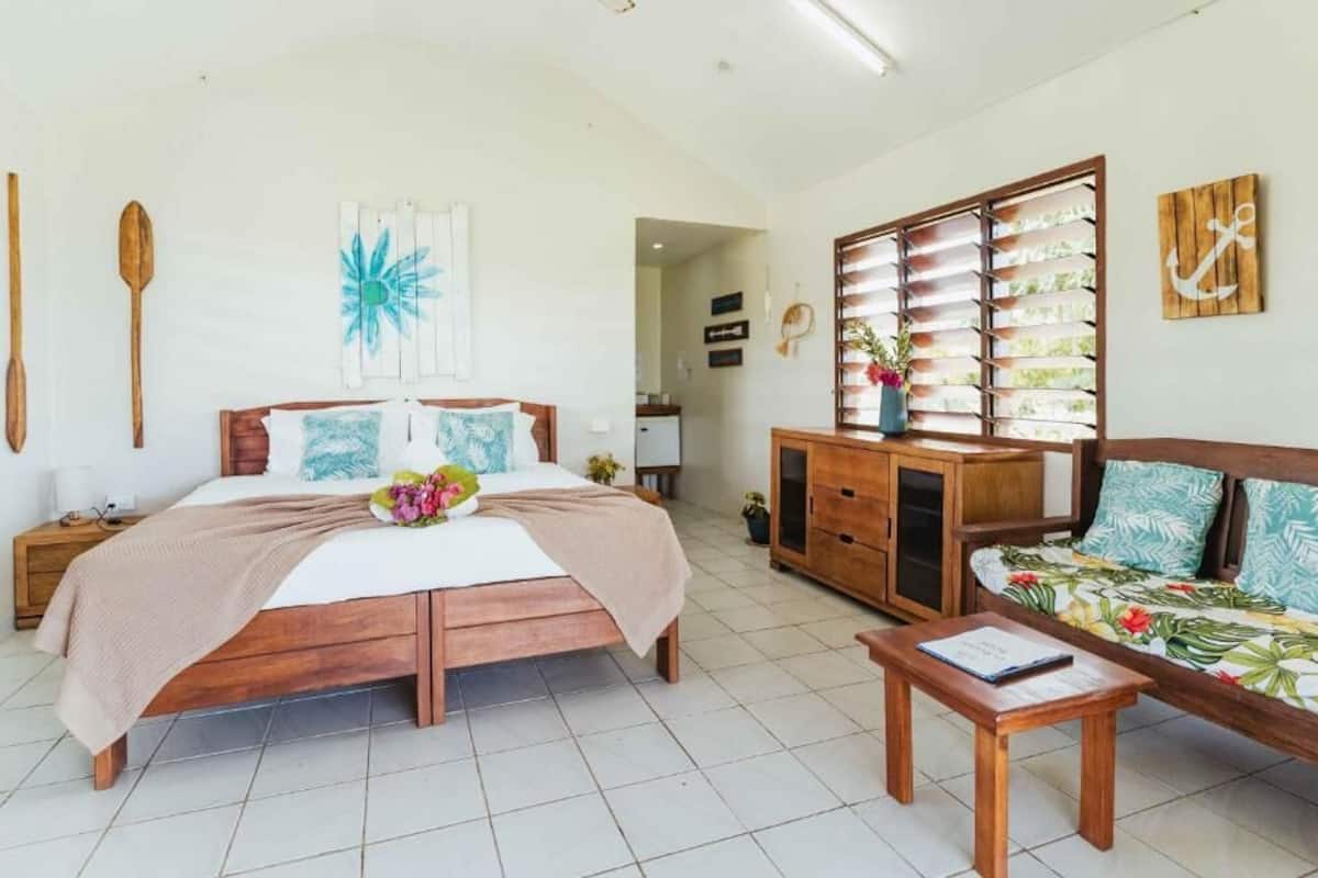 A bedroom with a wooden bed, a wooden nightstand, a wooden dresser, a wooden bench, and a wooden table.