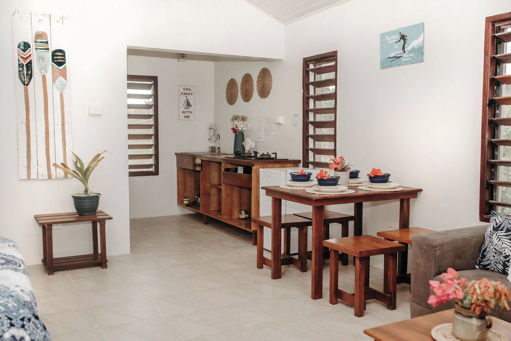 Un espacio habitable compacto con kitchenette, una zona de comedor con muebles de madera y un pequeño rincón de descanso.
