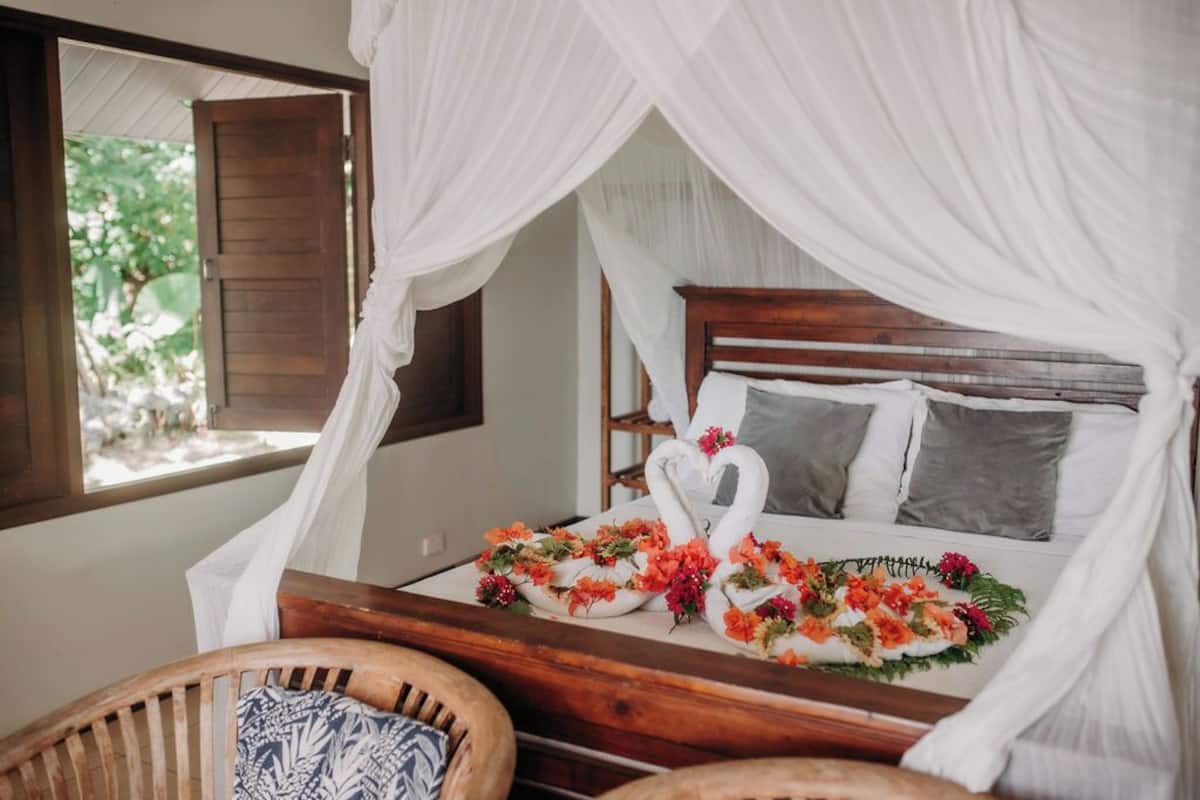 A bed with a canopy, a wooden headboard, and floral decorations.