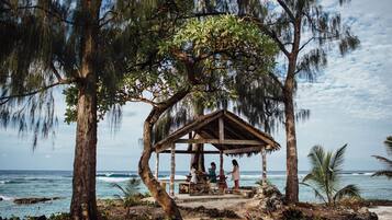 A wooden gazebo with a natural backdrop, overlooking the ocean.