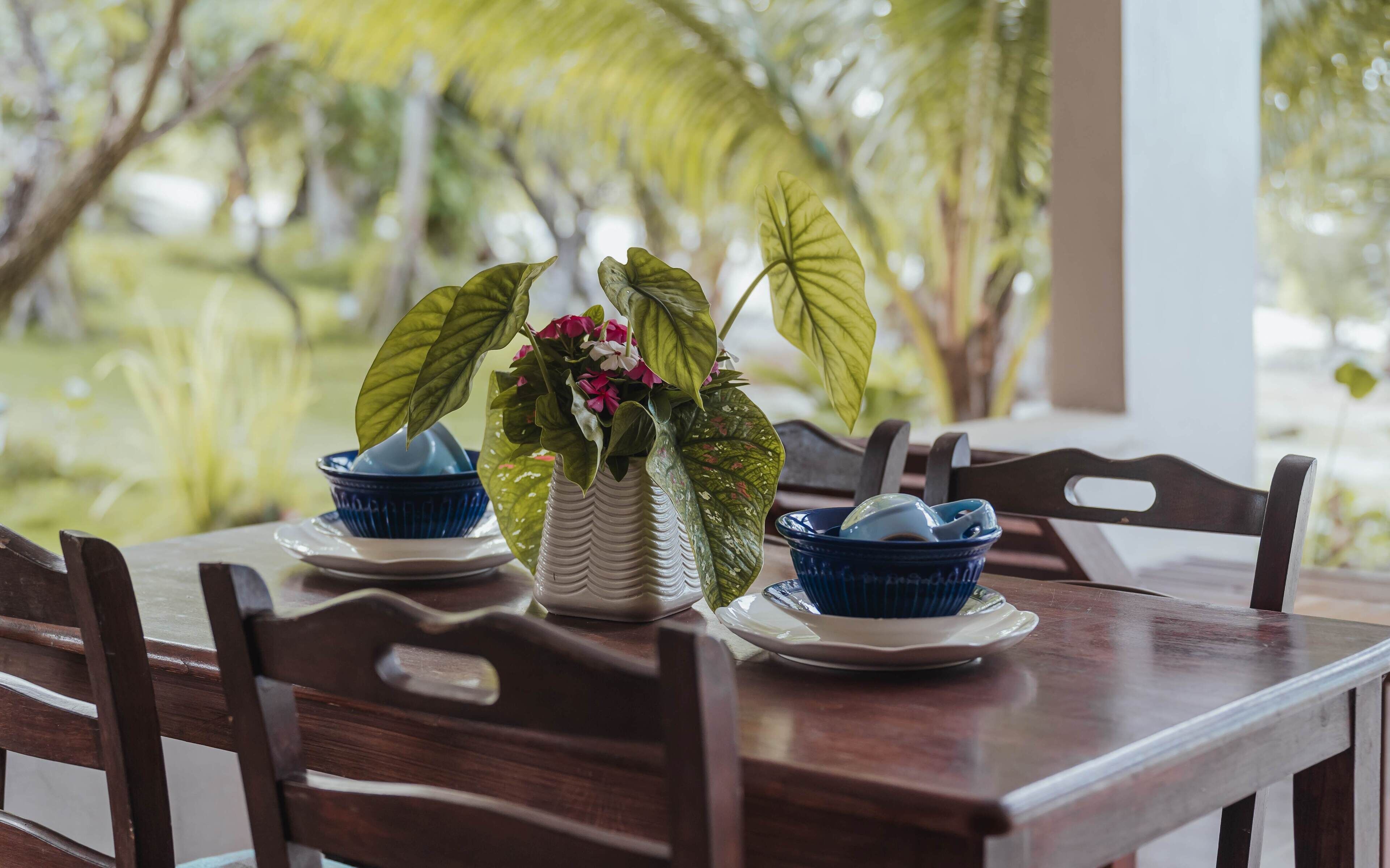 Una mesa de madera con dos cuencos azules y un jarrón blanco con flores.