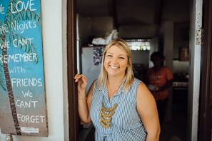 A person standing in a doorway with a sign on the wall that reads "We love the nights we can't remember with friends we can't forget." - Le Life Resort (Epule)