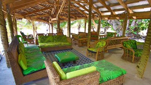 An outdoor seating area with wicker furniture and green cushions.