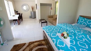 A bedroom with a bed, a sofa, a desk, and a chair.
