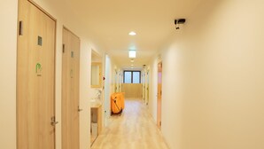 A hotel hallway with wooden doors, a shower area, and a camera on the ceiling. - J-Hoppers Osaka Universal - Hostel (Osaka)