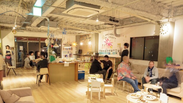 A spacious indoor area with wooden floors, multiple seating arrangements including sofas and tables, and a bar area. - J-Hoppers Osaka Universal - Hostel (Osaka)
